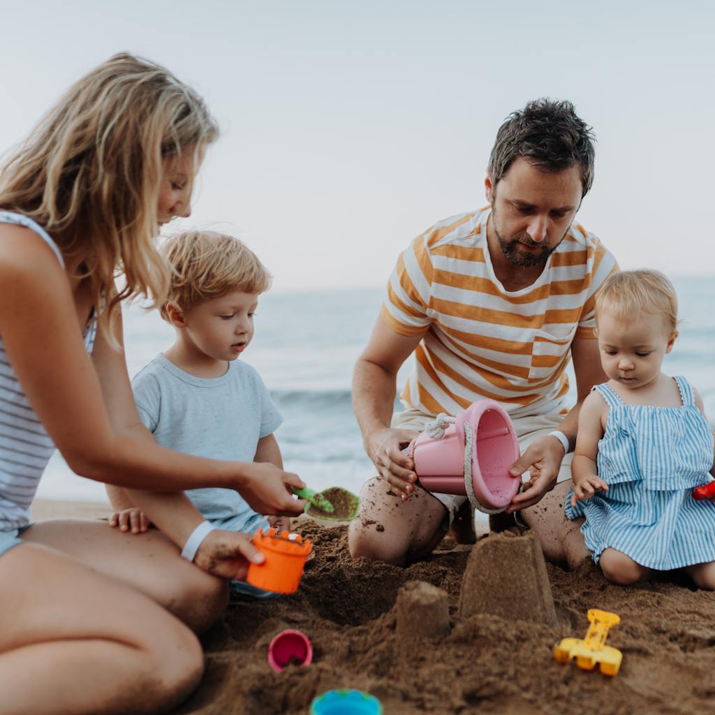 Familie baut Sandburg am Strand