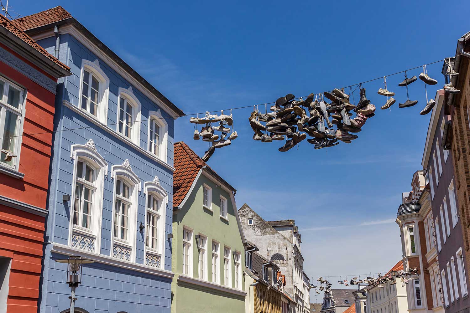Schuhe hängen an einer quer über die Straße gespannten Leine.