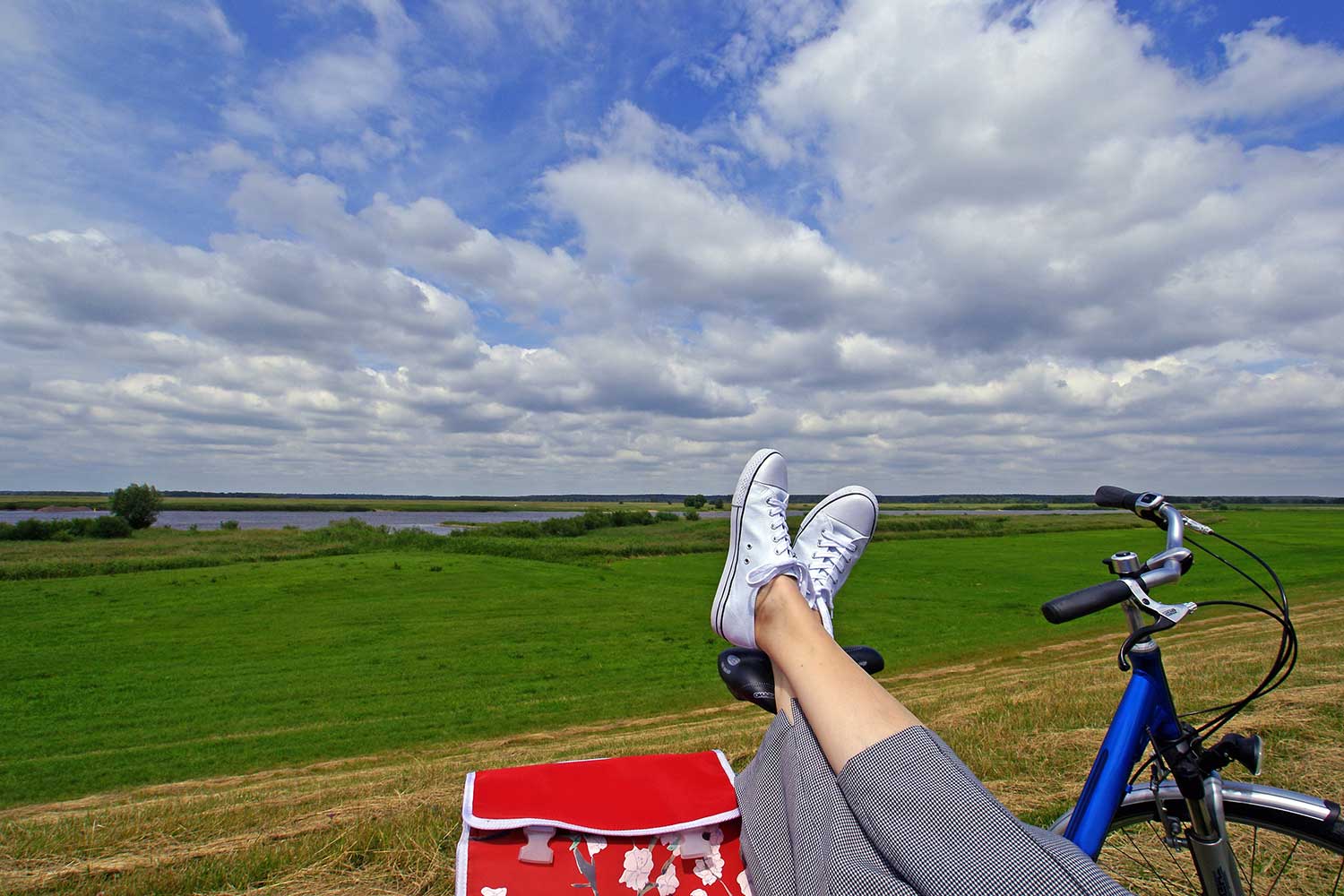 Kleine Pause am Elberadweg bei Glückstadt – ausgestreckte Frauenbeine liegen auf dem Fahrradsattel.