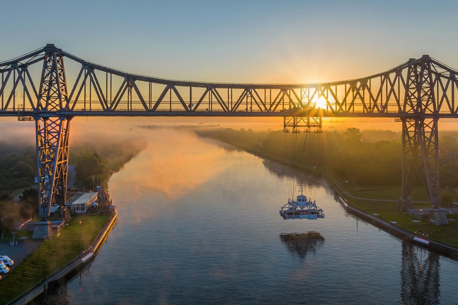 Panoramablick auf die berühmte Rendsburger Hochbrücke am Nord-Ostsee-Kanal mit der Schwebebrücke und dem Wohnwagenstellplatz am Morgen.im Morgenrot.